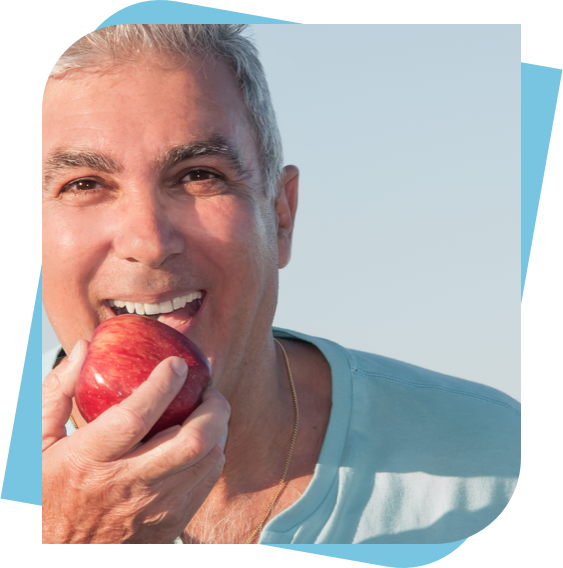 middle aged man smiling before taking a bite out of an apple