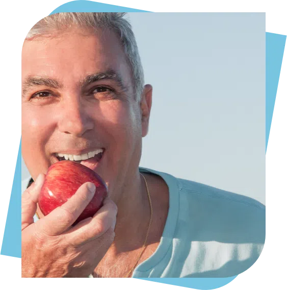middle aged man smiling before taking a bite out of an apple