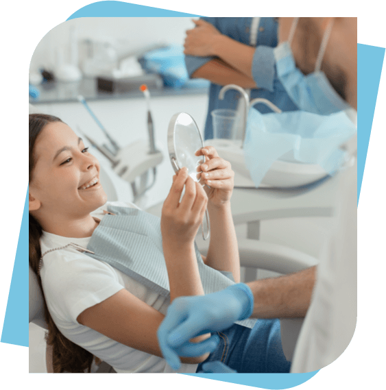 young girl in a dental chair checking out her smile in a mirror