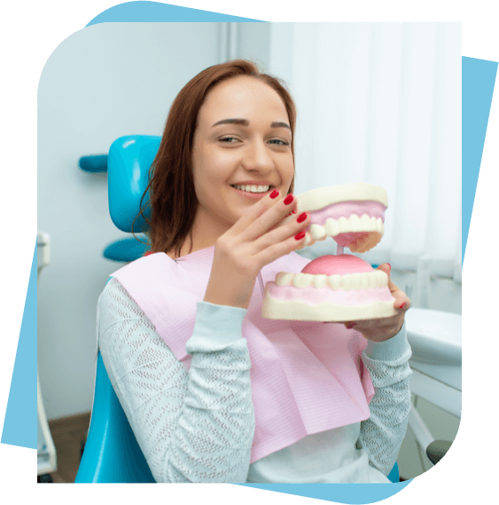 woman sitting in a dental chair holding a dental model.