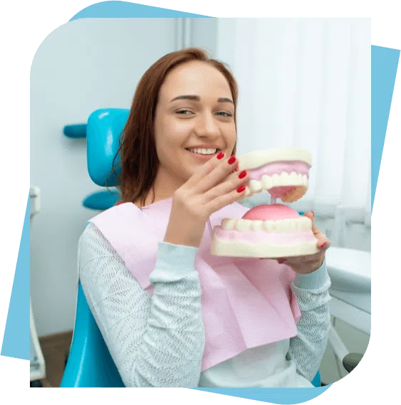 woman sitting in a dental chair holding a dental model.
