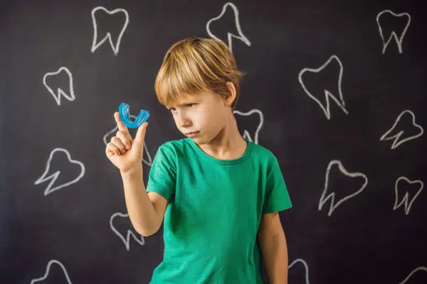 young boy holding nightguards in his right hand