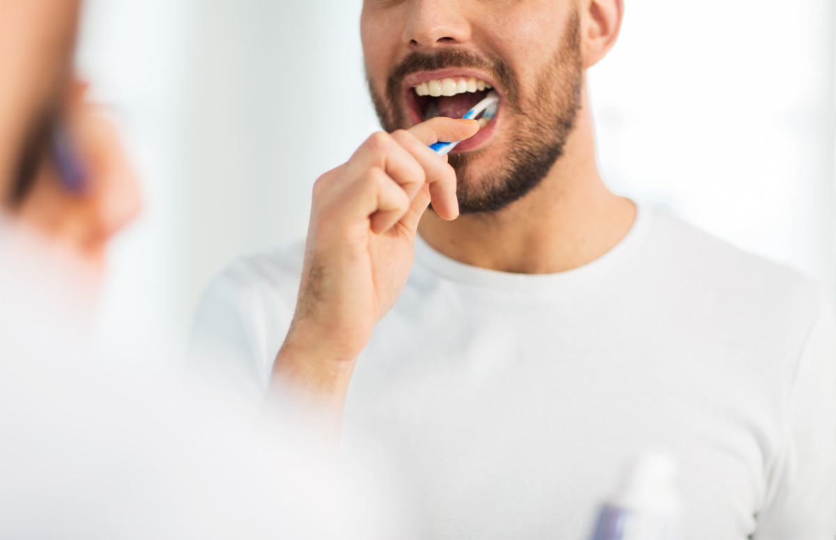man brushing his teeth to take care of his oral health
