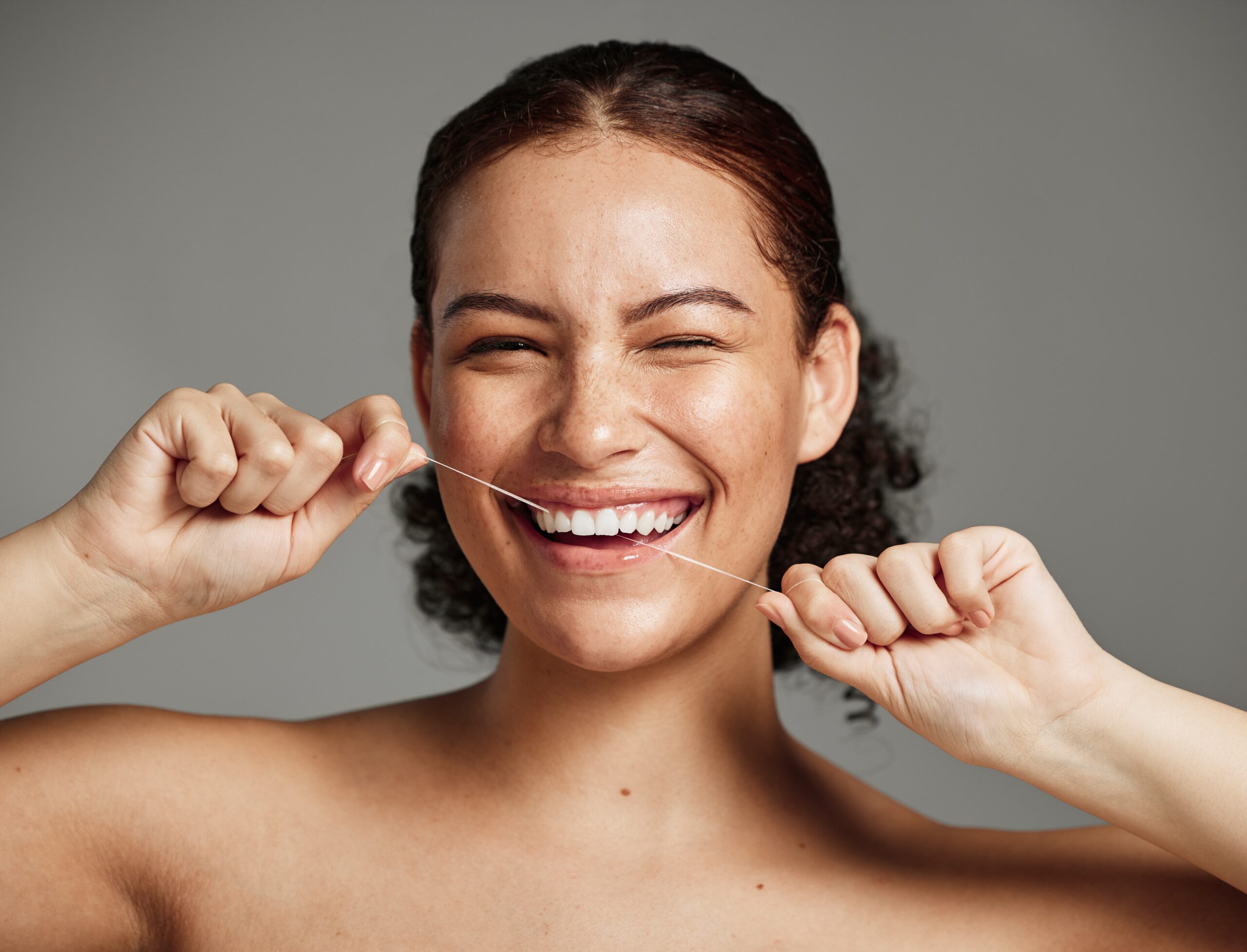 woman with a smile flossing teeth